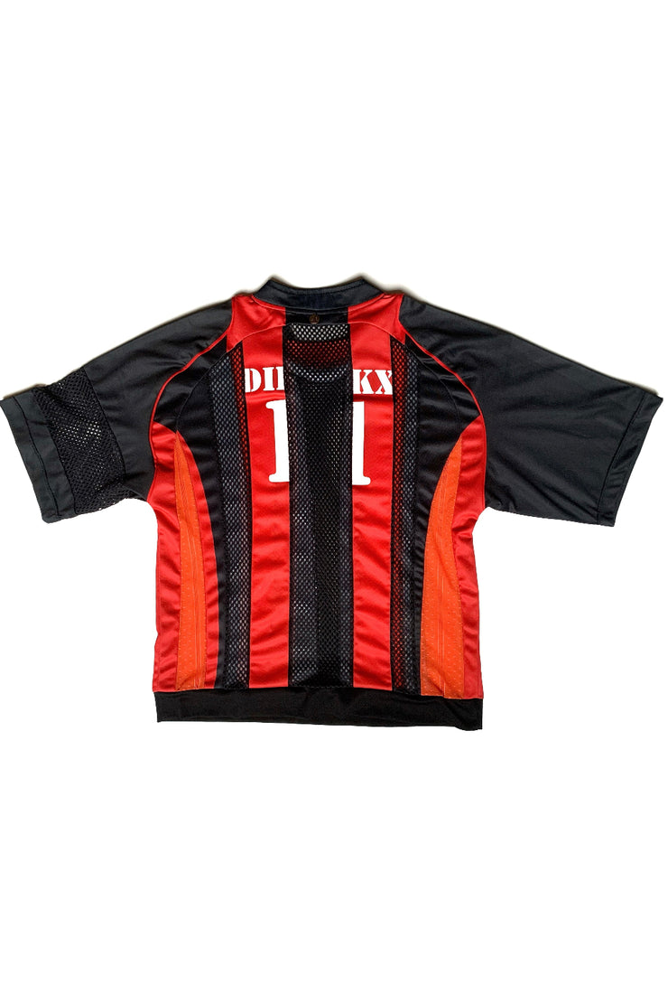 Maillot de foot upcyclé à rayures en résille noires et jersey rouges et orange de dos sur fond blanc