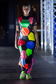 Défilé Football X Fashion, robe longue en patchwork de motifs, inspirée d'un icosaèdre ballon de football, silhouette complétée avec les chaussettes brodées rose et les chaussures de futsal customisées vert fluo 
