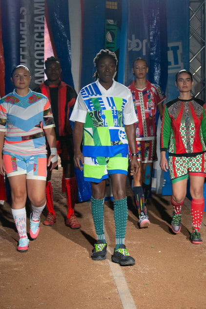 image du défilé montrant le look en contexte du projet football fashion upcyclé bleu blanc vert fluo avec chaussettes brodées. ©Damien Duponcheele