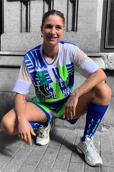 ensemble football bleu blanc vert fluo porté par une belle personne super cool en position accroupie