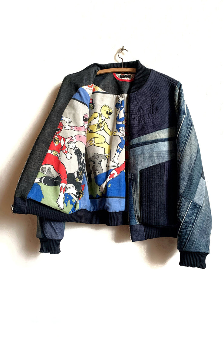 veste bomber réversible sur cintre, ouverte sur un côté laissant voir la doublure imprimée avec des Power Rangers. Surcyclage artisanal fabriqué à Bruxelles. 